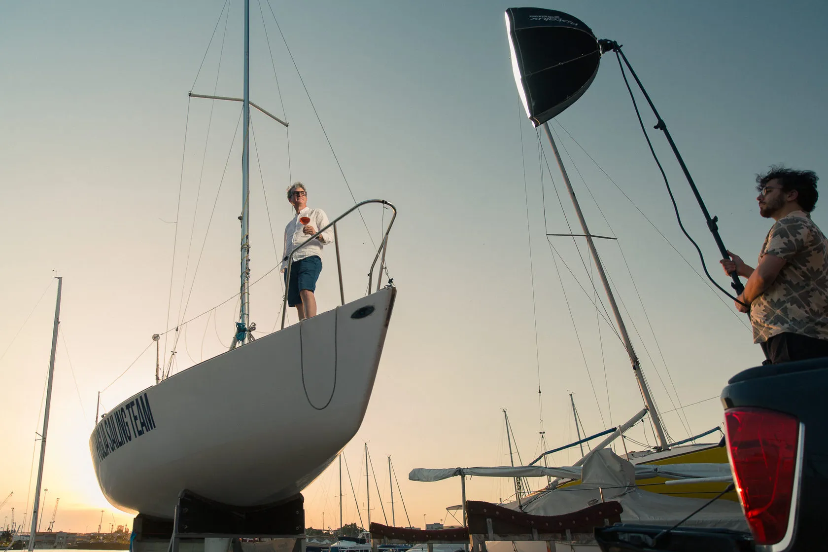 Behind the scenes: the yacht stands on dry land at dusk while a crew member holds up a light.