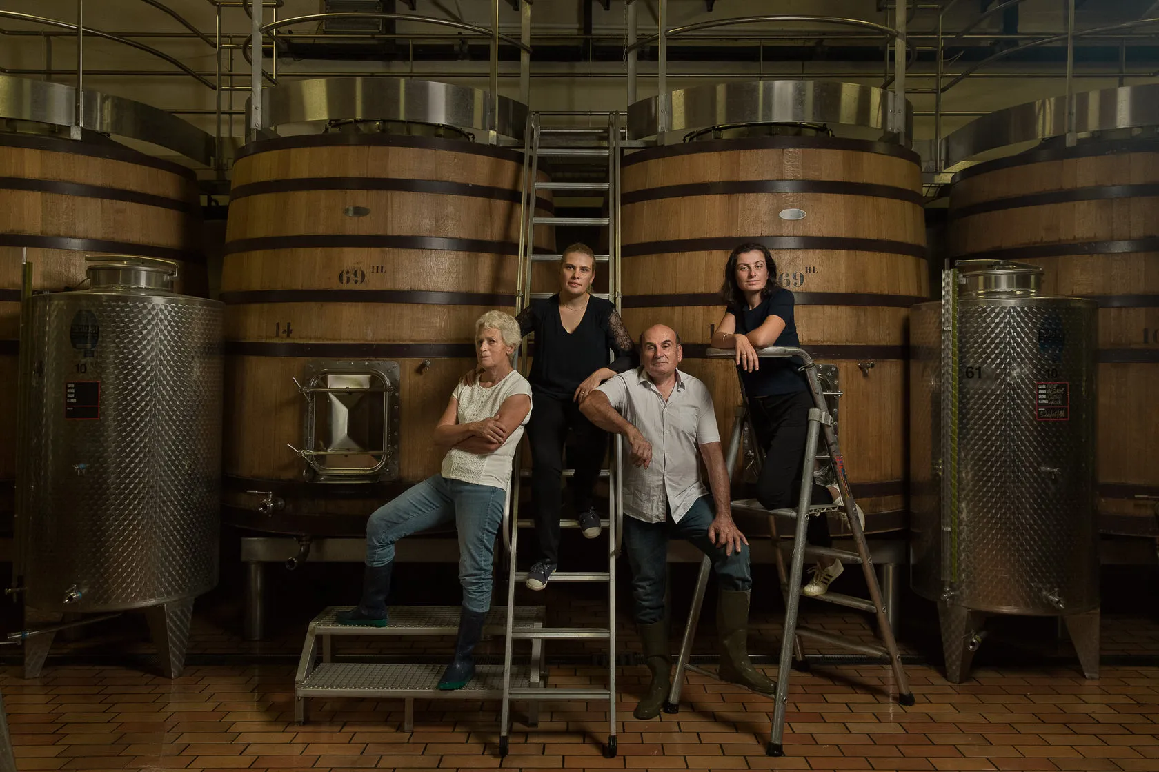 The Maret family by a ladder among oak vats and steel tanks.