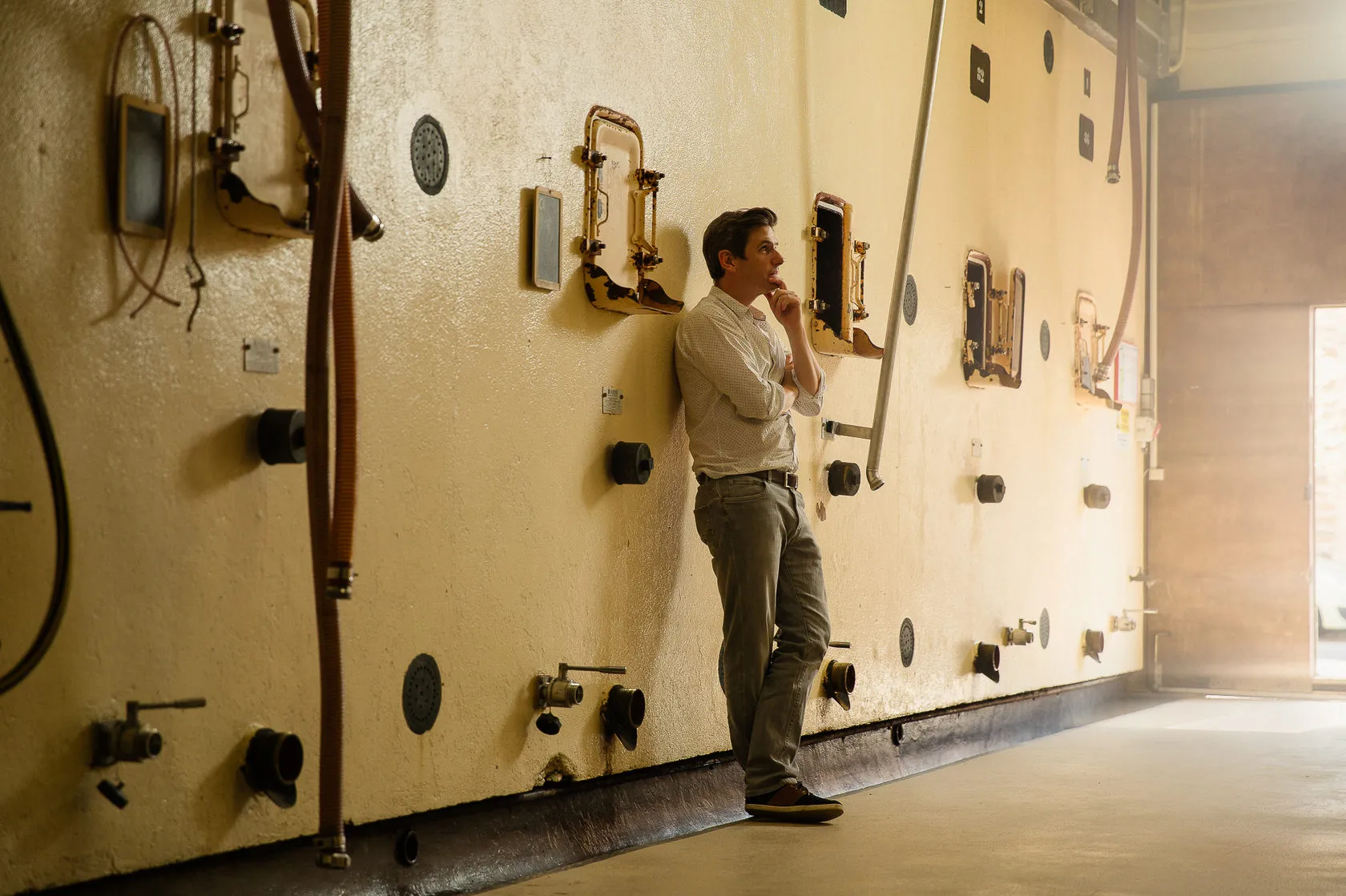 Antoine Dupré stands by a wall of old concrete vats, hand to his chin.