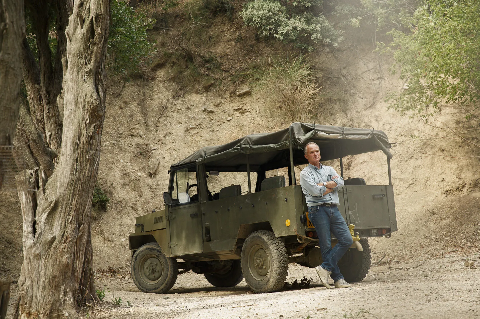 Daniel Brunier leans on an old army truck by a dusty track.